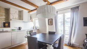 A modern kitchen with white cabinets, a dark wooden table, and a hanging light fixture. - LOCATED IN ONE OF PARIS’S MOST ICONIC NEIGHBORHOODS SAINT GERMAIN - RUE DRAGON  (Paris)