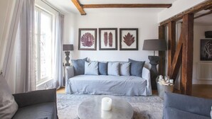 A bedroom with a bed, a nightstand, a lamp, a window with curtains, and framed leaf artwork on the wall. - LOCATED IN ONE OF PARIS’S MOST ICONIC NEIGHBORHOODS SAINT GERMAIN - RUE DRAGON  (Paris)