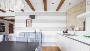 A modern kitchen with white cabinetry, a wooden dining table, and a hanging light fixture. - LOCATED IN ONE OF PARIS’S MOST ICONIC NEIGHBORHOODS SAINT GERMAIN - RUE DRAGON  (Paris)