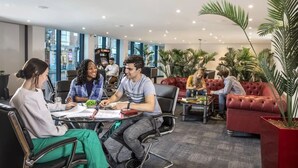 Et moderne loungeområde med lædersofaer, et sofabord og potteplanter.