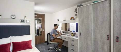 Una habitación de hotel con cama, escritorio y armario.