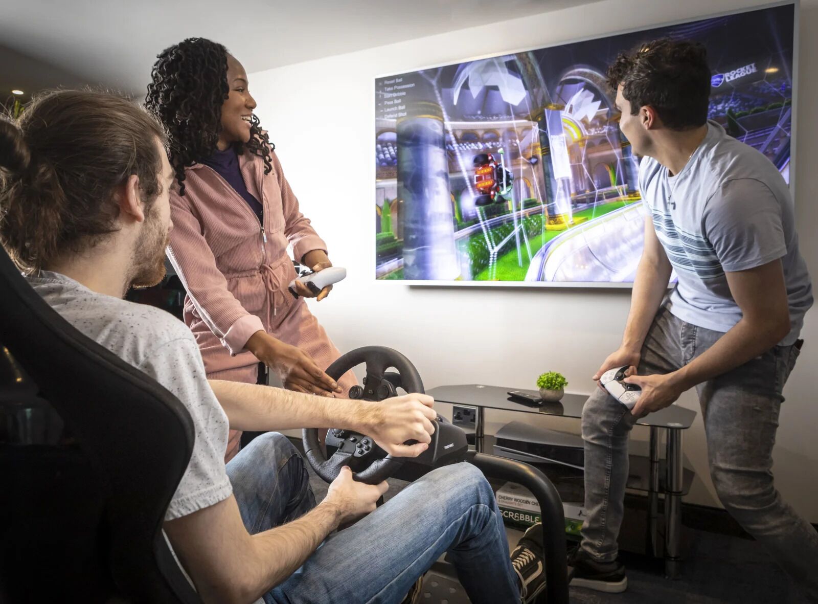 Un grupo de personas jugando un videojuego de carreras en una habitación con una pantalla grande mostrando el juego.