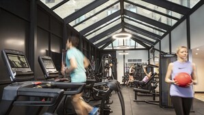 Et træningscenter med løbebånd, styrkemaskiner og et stort ovenlys.