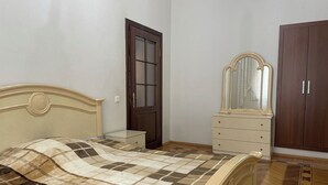 Ein Schlafzimmer mit Bett, Kommode, Spiegel, Kleiderschrank und Tür.