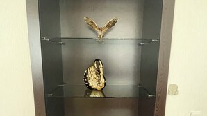 Eine Vitrine mit drei Ablagen, auf jeder eine Dekoration.