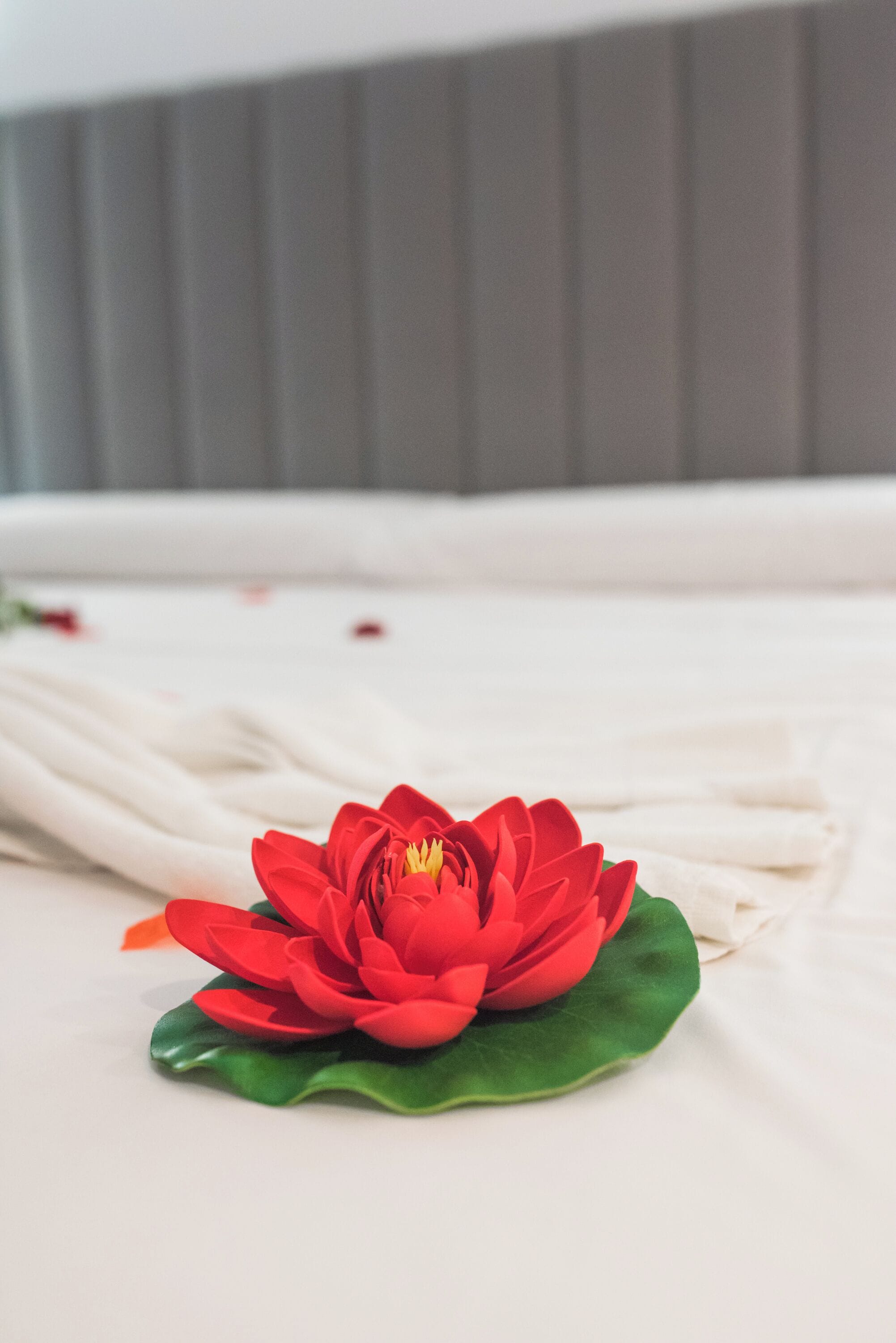 Un lit avec un drap blanc et une décoration florale rouge.
