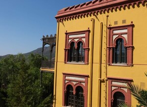 Un edificio amarillo con marcos de ventana rojos y un balcón.