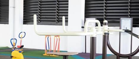 A gym with exercise equipment, including a bench, a pull-up bar, and a stationary bike.