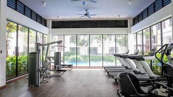 A gym with treadmills, a ceiling fan, and large windows.