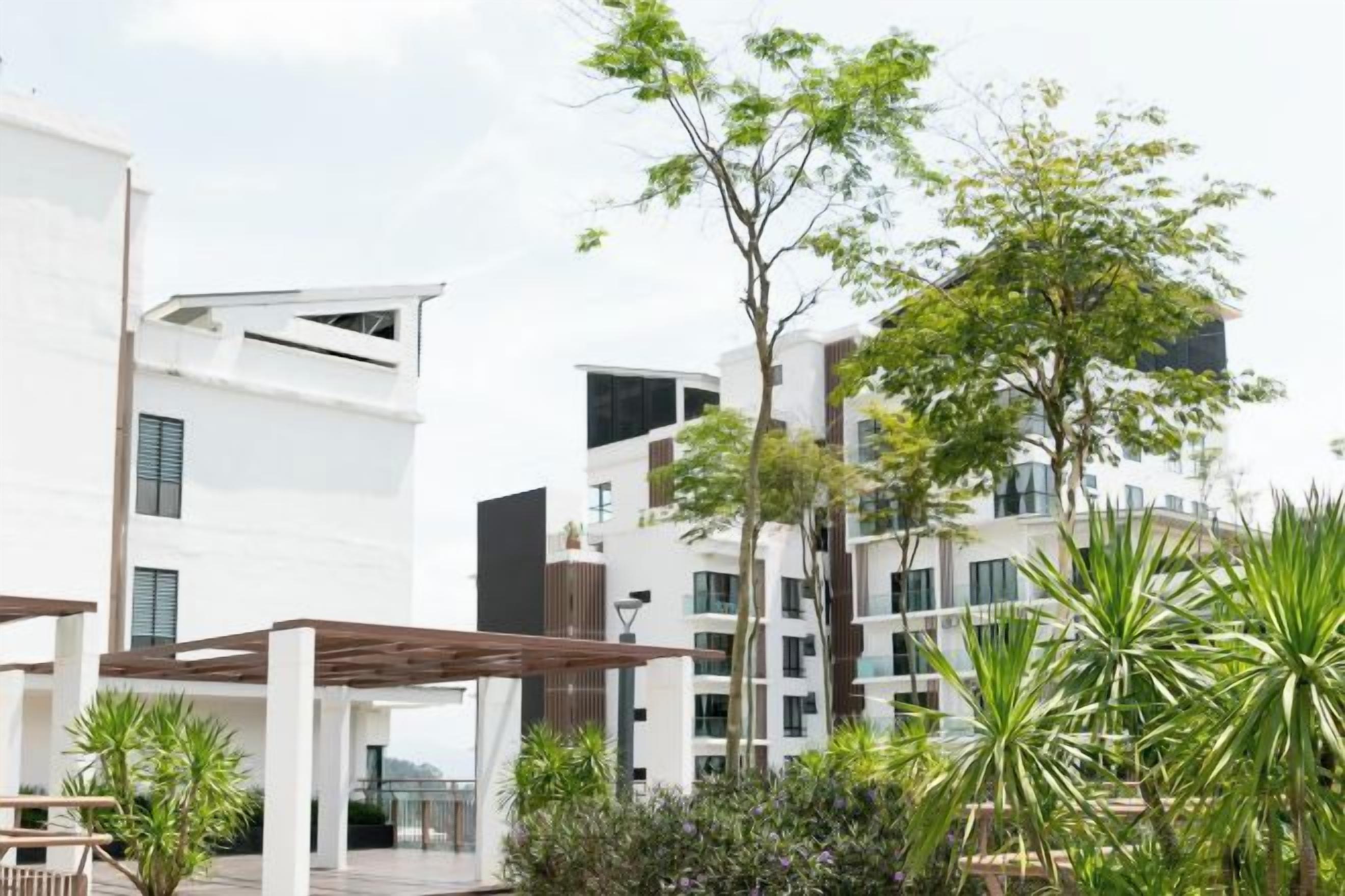 A modern residential complex with multiple-story buildings, outdoor seating areas, and greenery.