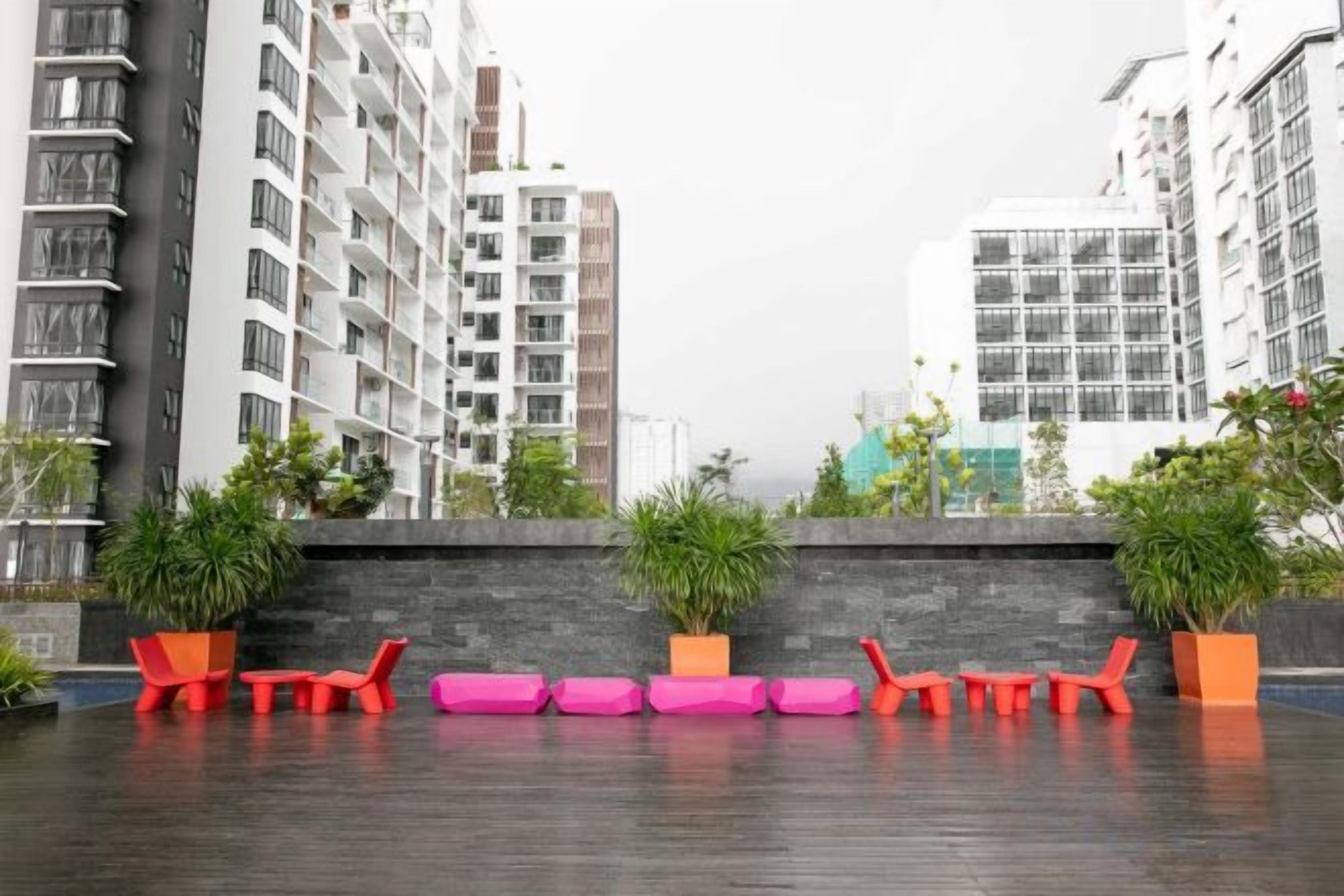 Une terrasse sur le toit, aménagée avec des sièges et des plantes en pot, entourée d’immeubles de grande hauteur.
