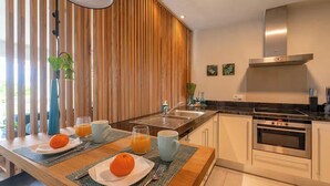 A modern kitchen with a central island, stainless steel appliances, and a view of the outdoors.