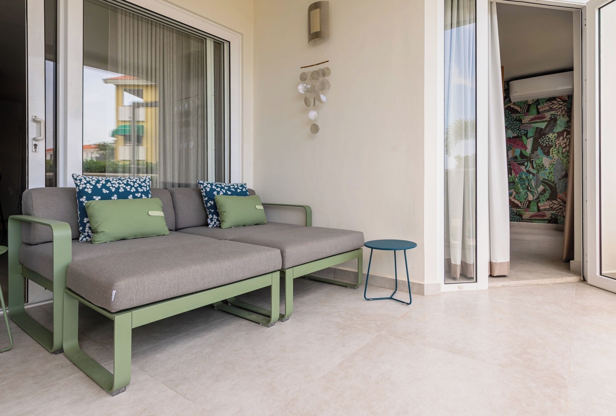 Een moderne zithoek met een zette, een bijzettafeltje en een schuifdeur naar een balkon.