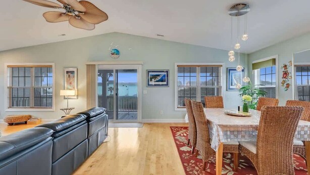 A spacious living room with a large sofa, dining table with chairs, and a ceiling fan. - Just Chillin' (Kure Beach)