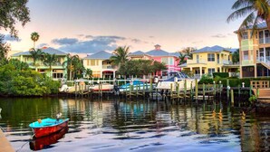 A waterfront property with multiple colorful buildings, docked boats, and lush greenery. - Paradise Palms, Private backyard w/ Pool, Hot tub! (Stuart)