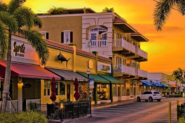 A street view at sunset with a building featuring a 'Spirit City Bistro' sign, a balcony, and a parked car. - Paradise Palms, Private backyard w/ Pool, Hot tub! (Stuart)
