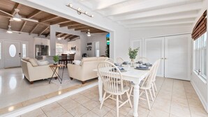 A spacious living area with a dining table and chairs, a sofa, and a kitchen in the background. - Paradise Palms, Private backyard w/ Pool, Hot tub! (Stuart)