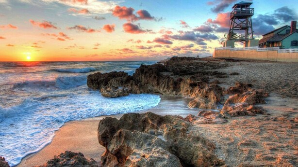 A coastal scene with a rocky shoreline, waves, and a lighthouse. - Paradise Palms, Private backyard w/ Pool, Hot tub! (Stuart)