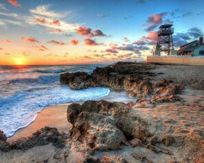 A coastal scene with a rocky shoreline, waves, and a lighthouse. - Paradise Palms, Private backyard w/ Pool, Hot tub! (Stuart)