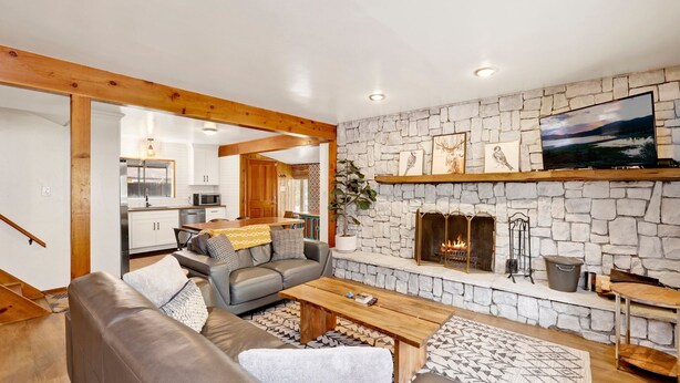 A modern living room with a stone fireplace, a dining area, and a kitchen in the background. - Sugar Bear Pines #2493 (Sugarloaf)