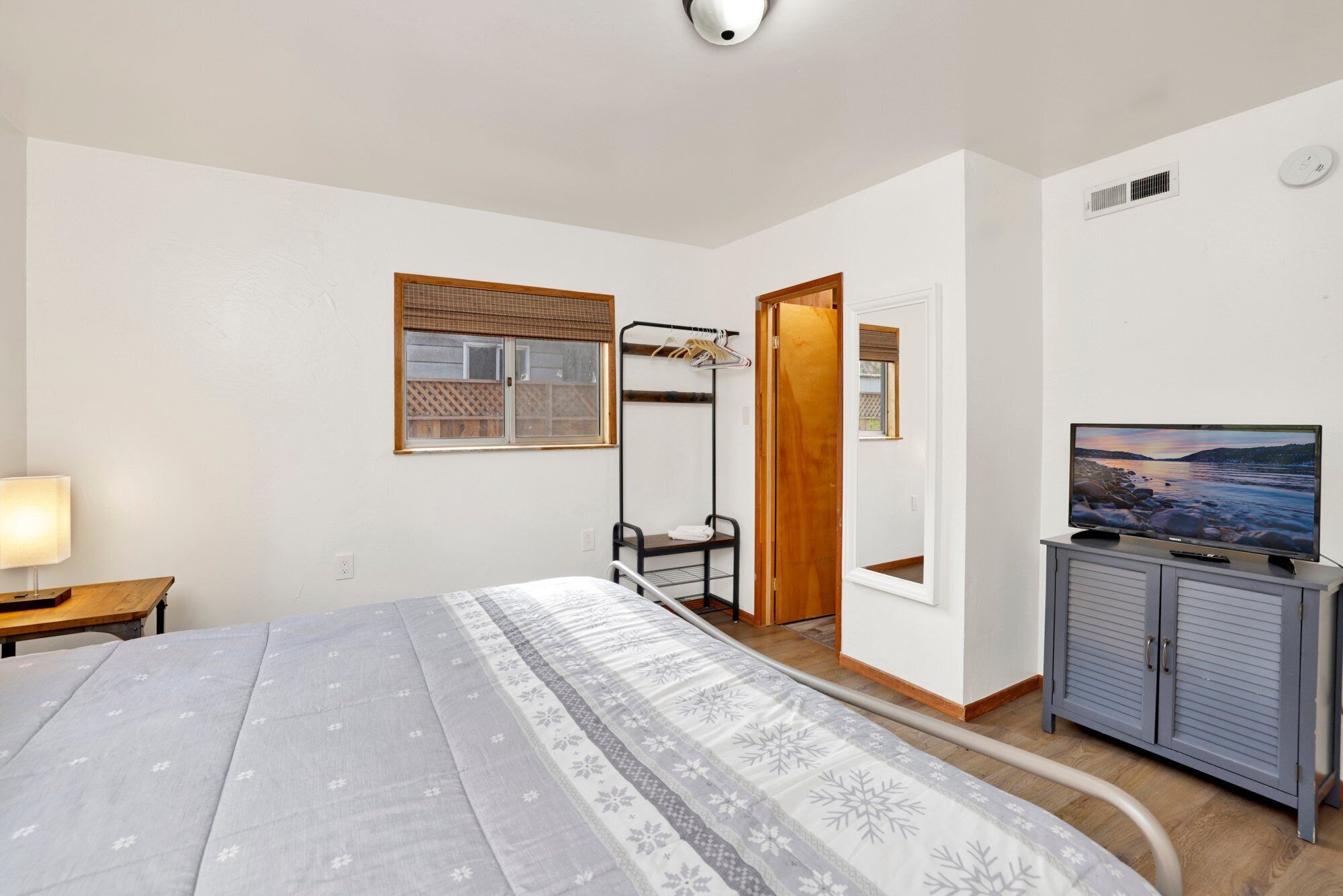 Un dormitorio con cama, televisor, armario, ventana y puerta.