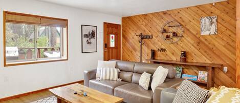 Een woonkamer met een houten wand, een bank, een salontafel en een vloerkleed.