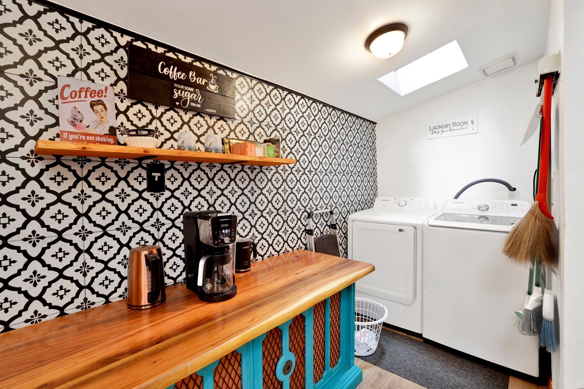 Una cocina funcional con cafetera, lavamanos y espacio para lavandería.