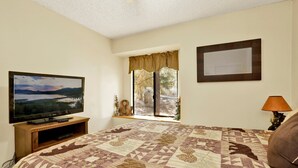 A bedroom with a large bed, a television, a window with curtains, and a lamp. - Rutter Family Retreat #2482 (Sugarloaf)