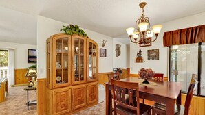 A dining room with a wooden cabinet, a chandelier, and a dining table with chairs. - Rutter Family Retreat #2482 (Sugarloaf)