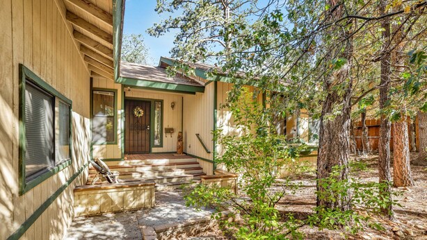 A wooden house with a front porch, steps leading to the door, and a small garden area with trees and shrubs. - Rutter Family Retreat #2482 (Sugarloaf)