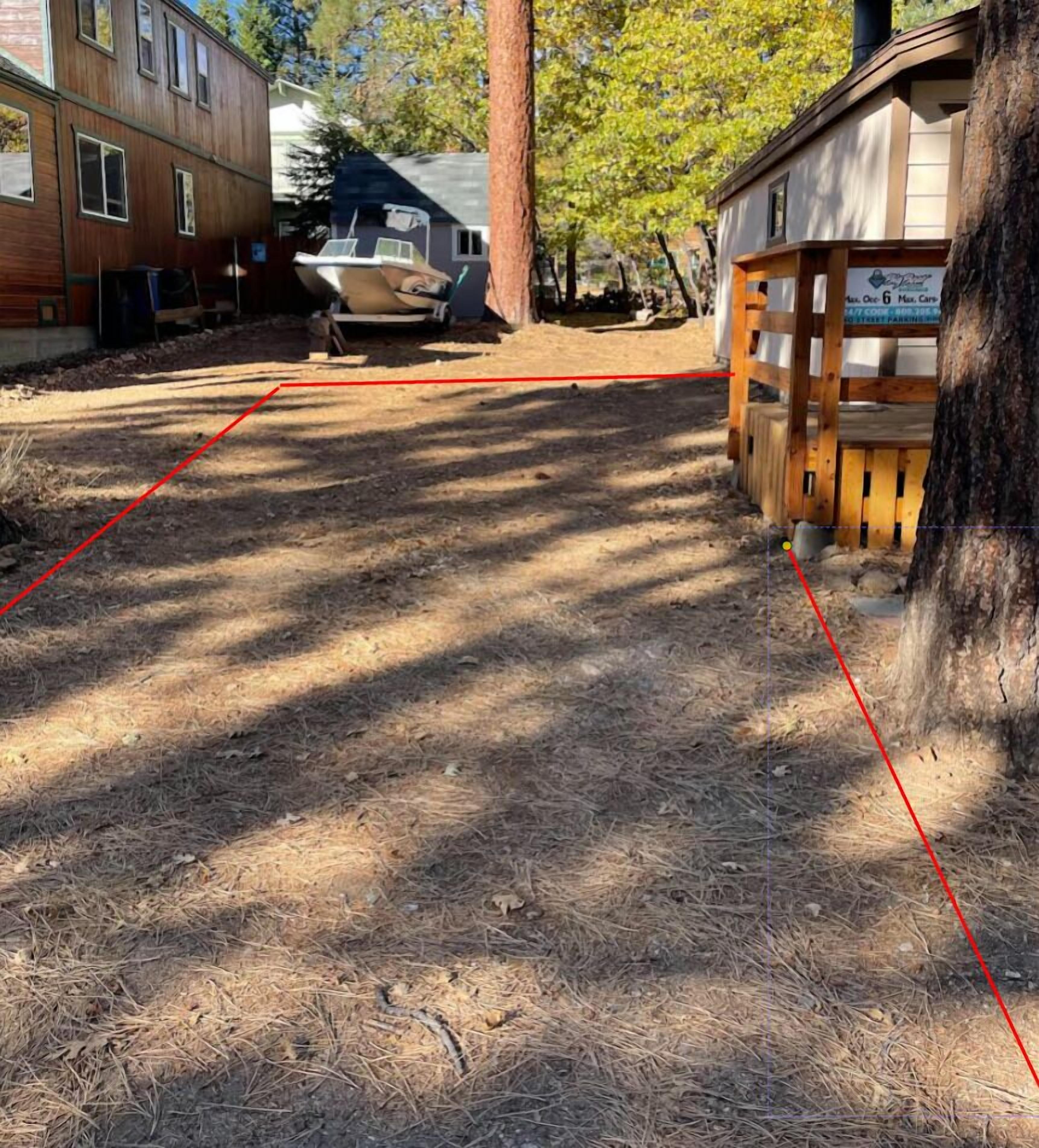 Un patio trasero con un bote, una terraza de madera y un árbol.