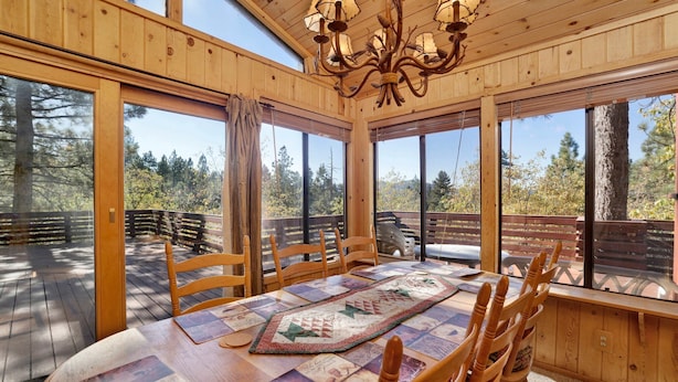 A wooden dining room with a large table, chairs, and a chandelier.