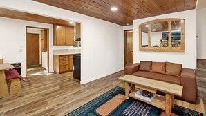 Una sala de estar con un sofá de cuero marrón, una mesa de centro de madera y un espejo grande en la pared.
