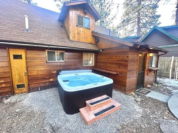 A wooden cabin with a hot tub, a door, and windows. - Highland Oaks Retreat #2492 (Sugarloaf)