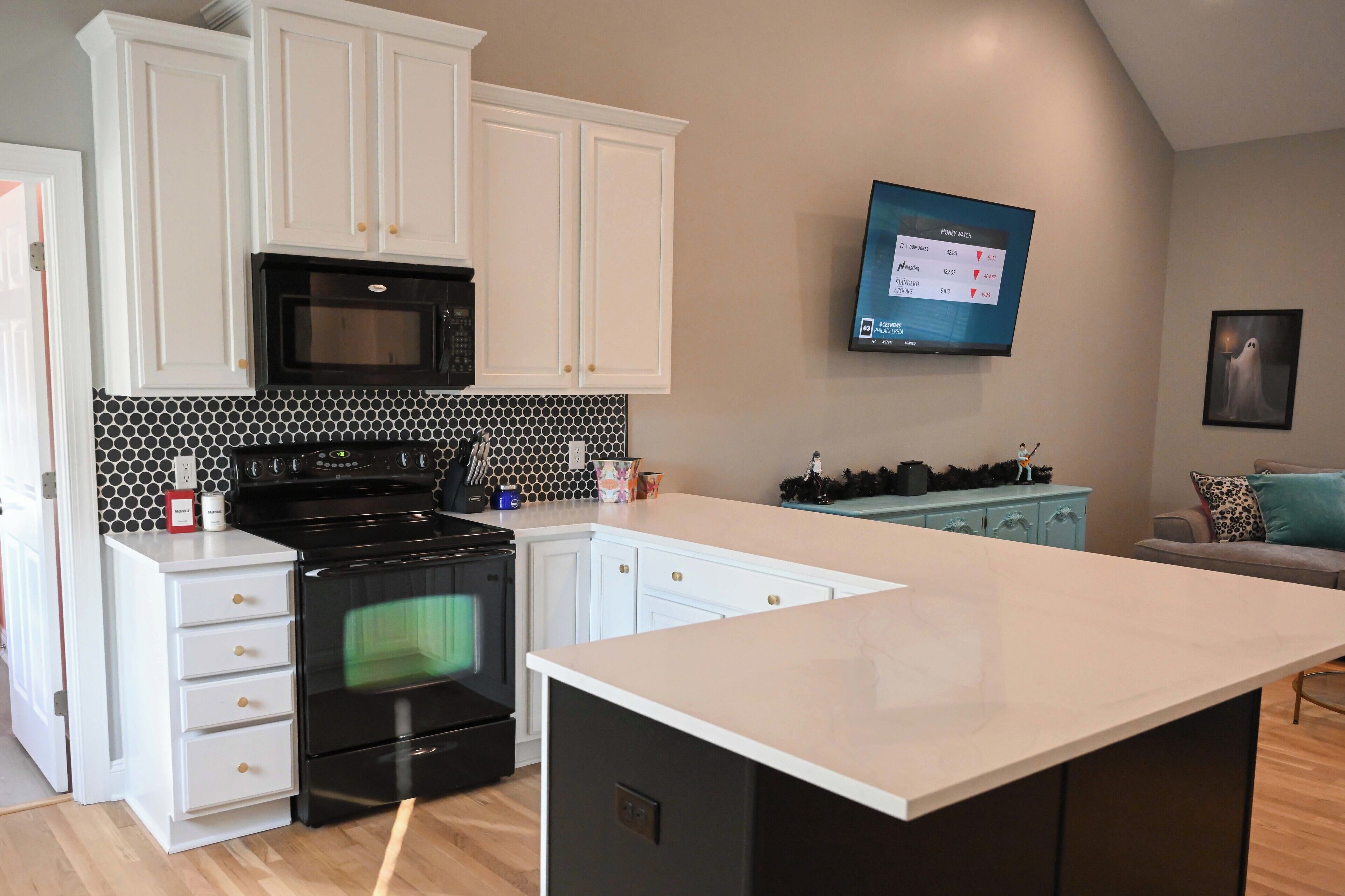 A modern kitchen with white cabinets, a black stove, and a large island.