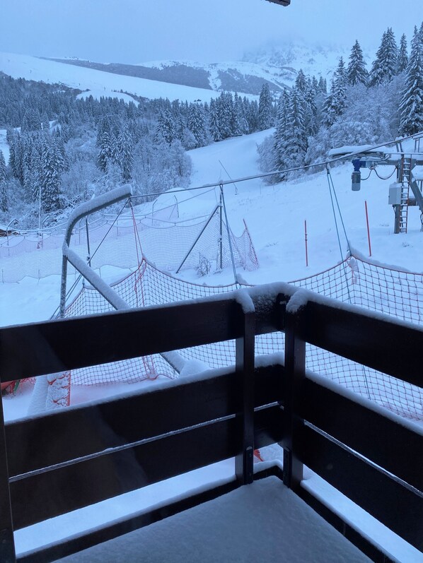 A snow-covered ski slope with a ski lift and netted area.