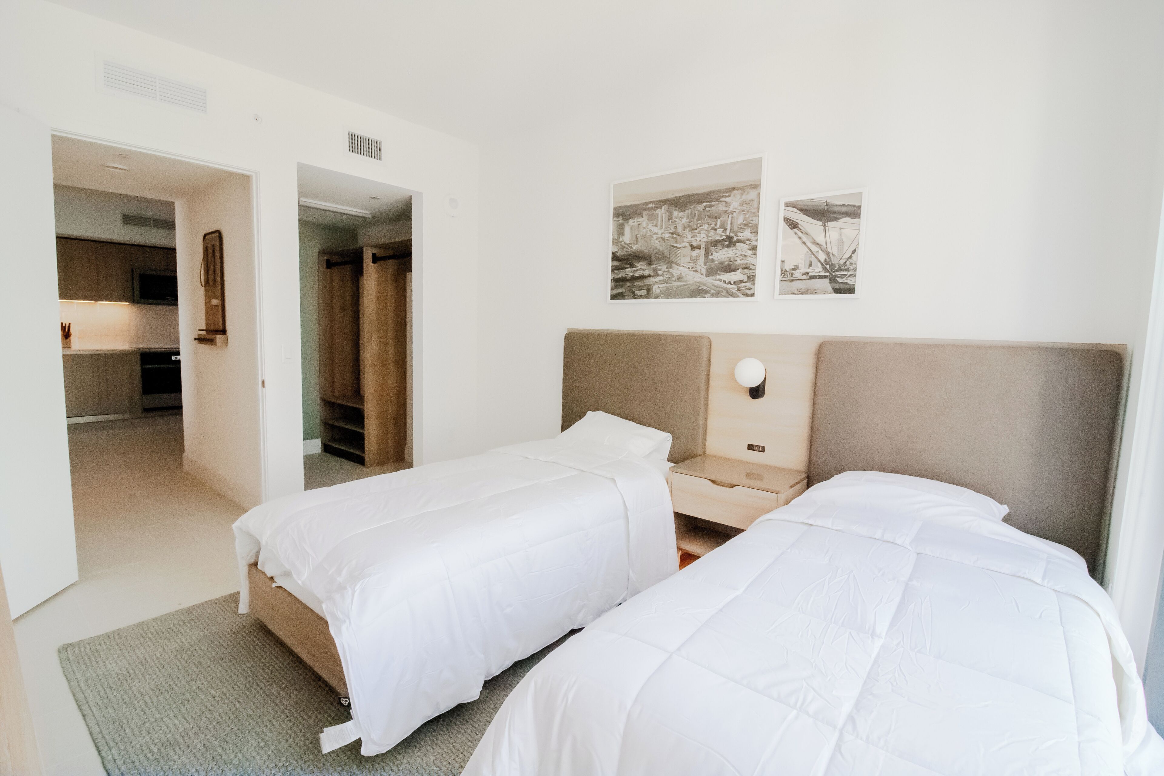 Habitación de hotel con dos camas, un escritorio pequeño y vista a la ciudad por la ventana.