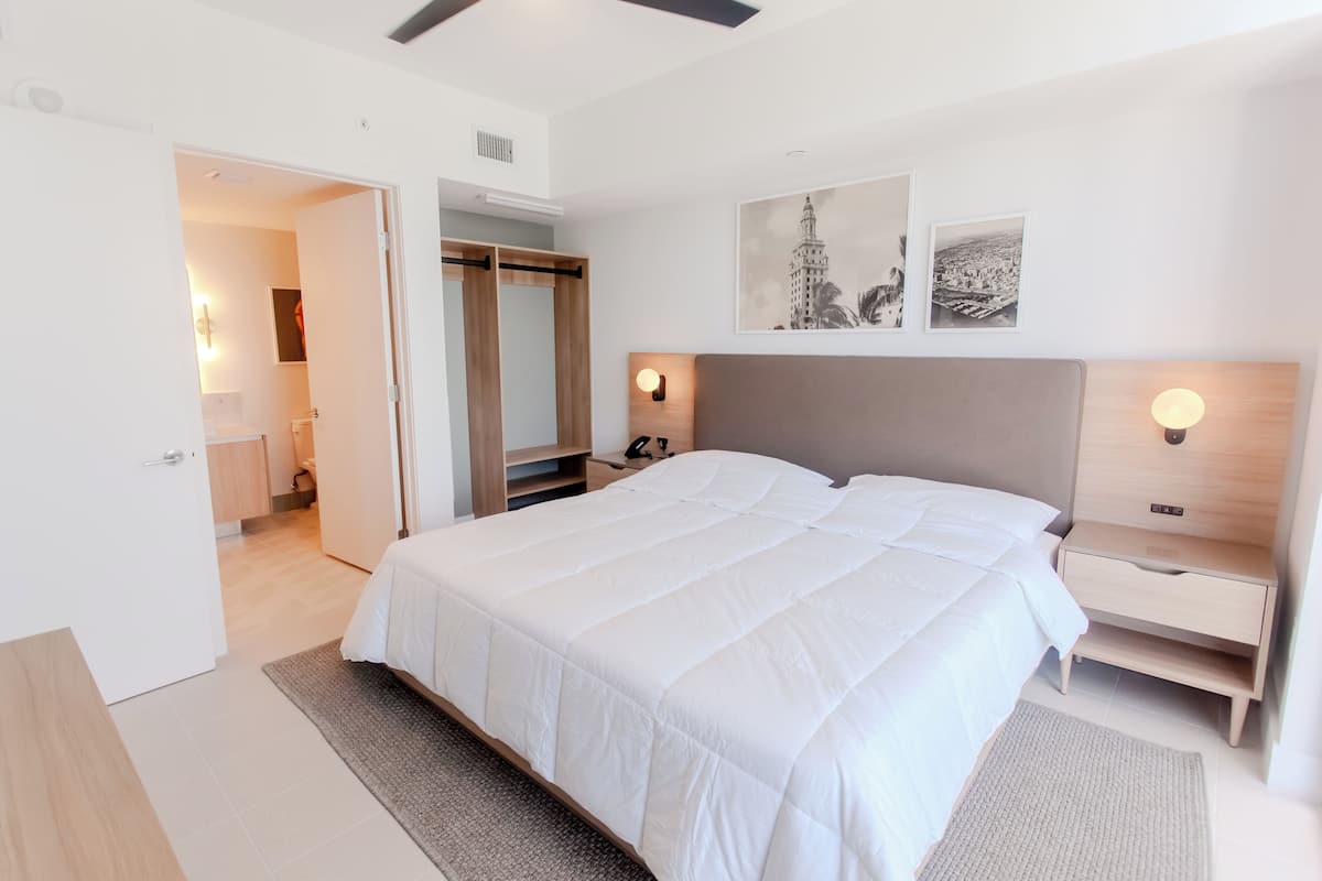 A modern bedroom with a large bed, bedside tables, and a wardrobe.