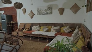 Ein gemütliches Wohnzimmer mit einer Couch, Korbstühlen, einem Couchtisch und einem Essbereich mit Tisch und Stühlen.