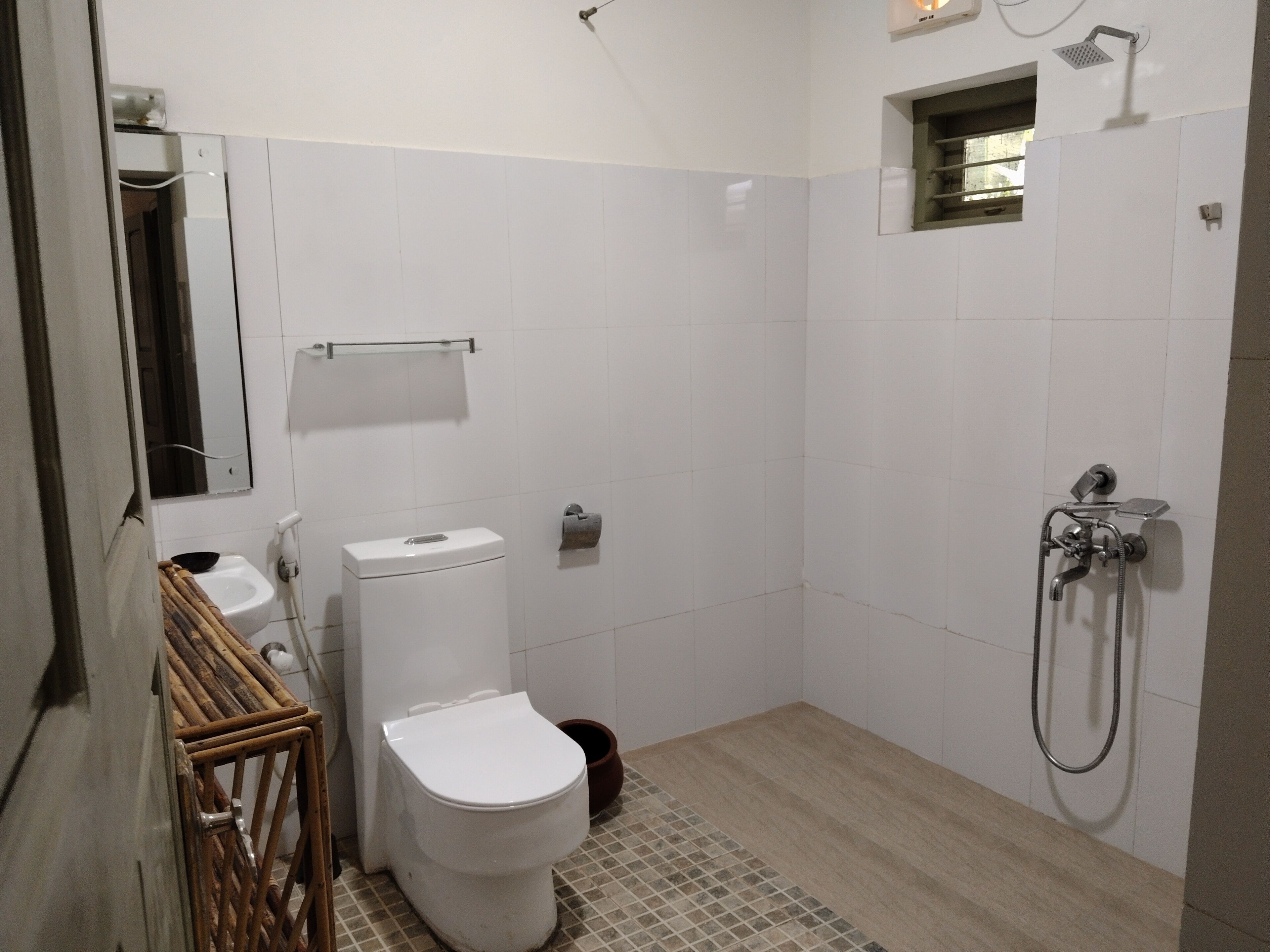A bathroom with a toilet, a shower, and a mirror.