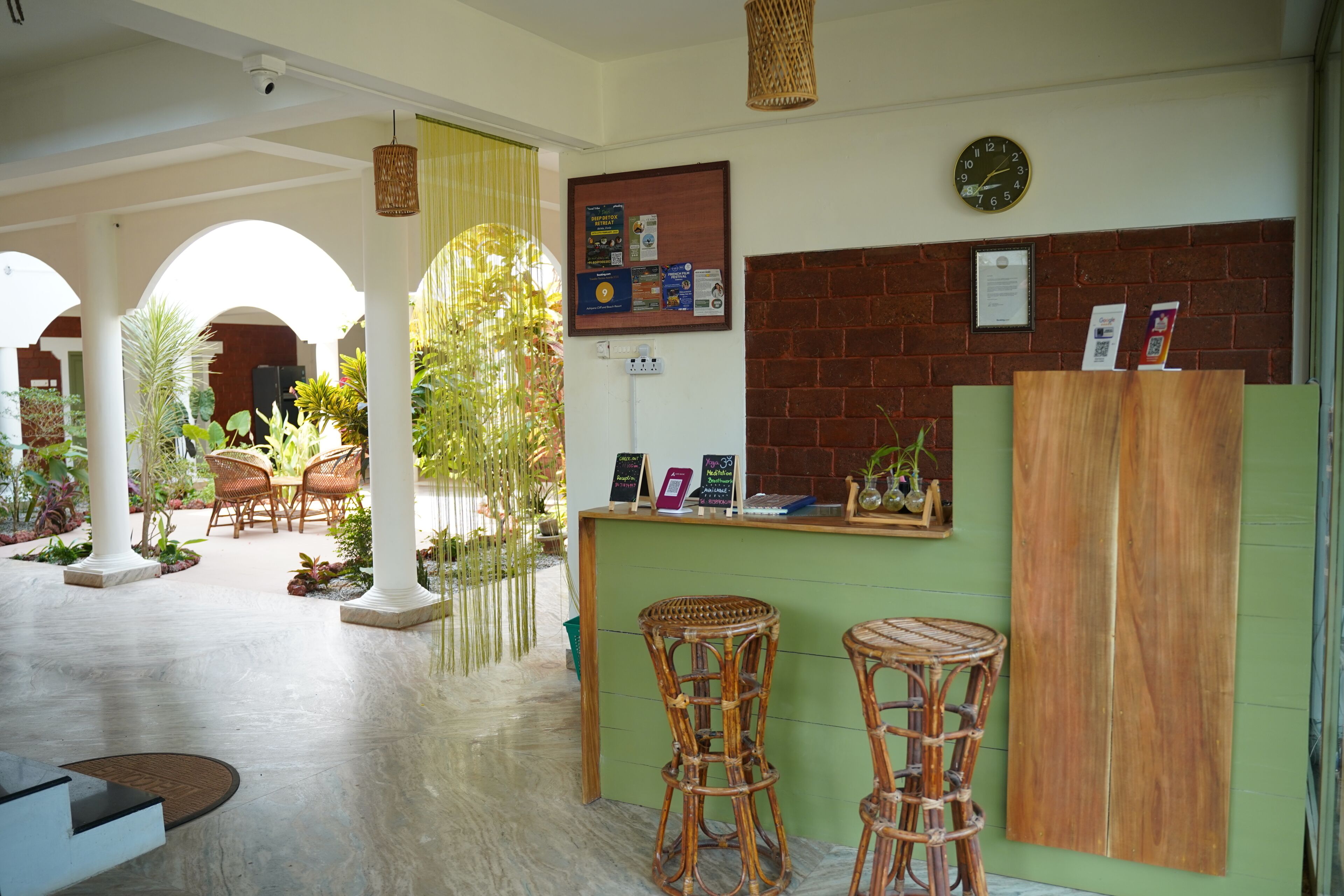 A reception area with a green counter, wicker chairs, and a brick wall.