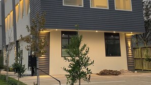 A modern building with a flat roof, large windows, and a balcony with railings. - Centrally located, unique and brand new condo (Houston)