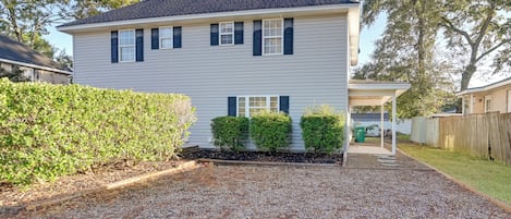 A two-story house with a gravel driveway and a covered porch.