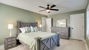 A bedroom with a bed, nightstands, a dresser, a ceiling fan, and a door. - 1 Mi to Pier: Screened Patio at Murrells Inlet Apt (Murrells Inlet)