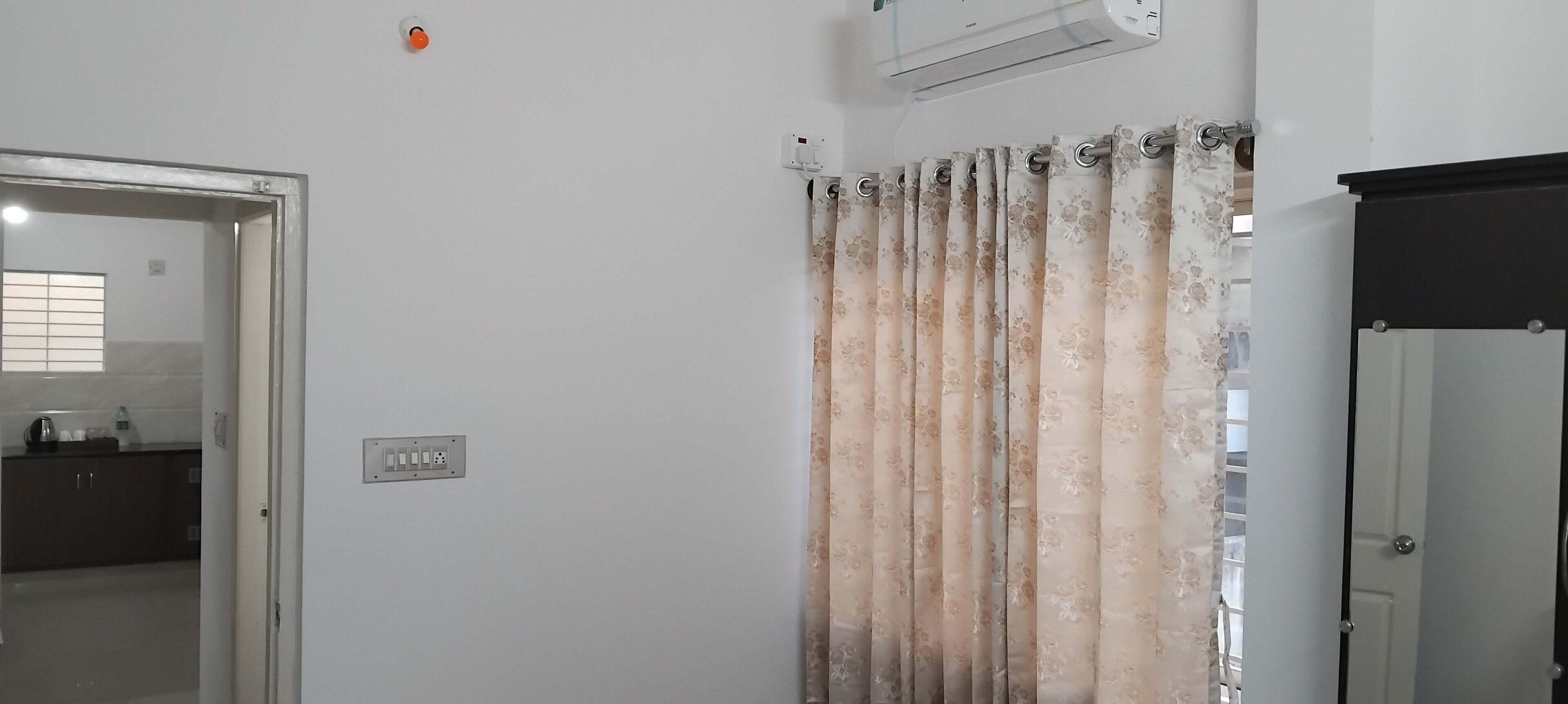 A room with a door, a power outlet, and a wall-mounted air conditioner.