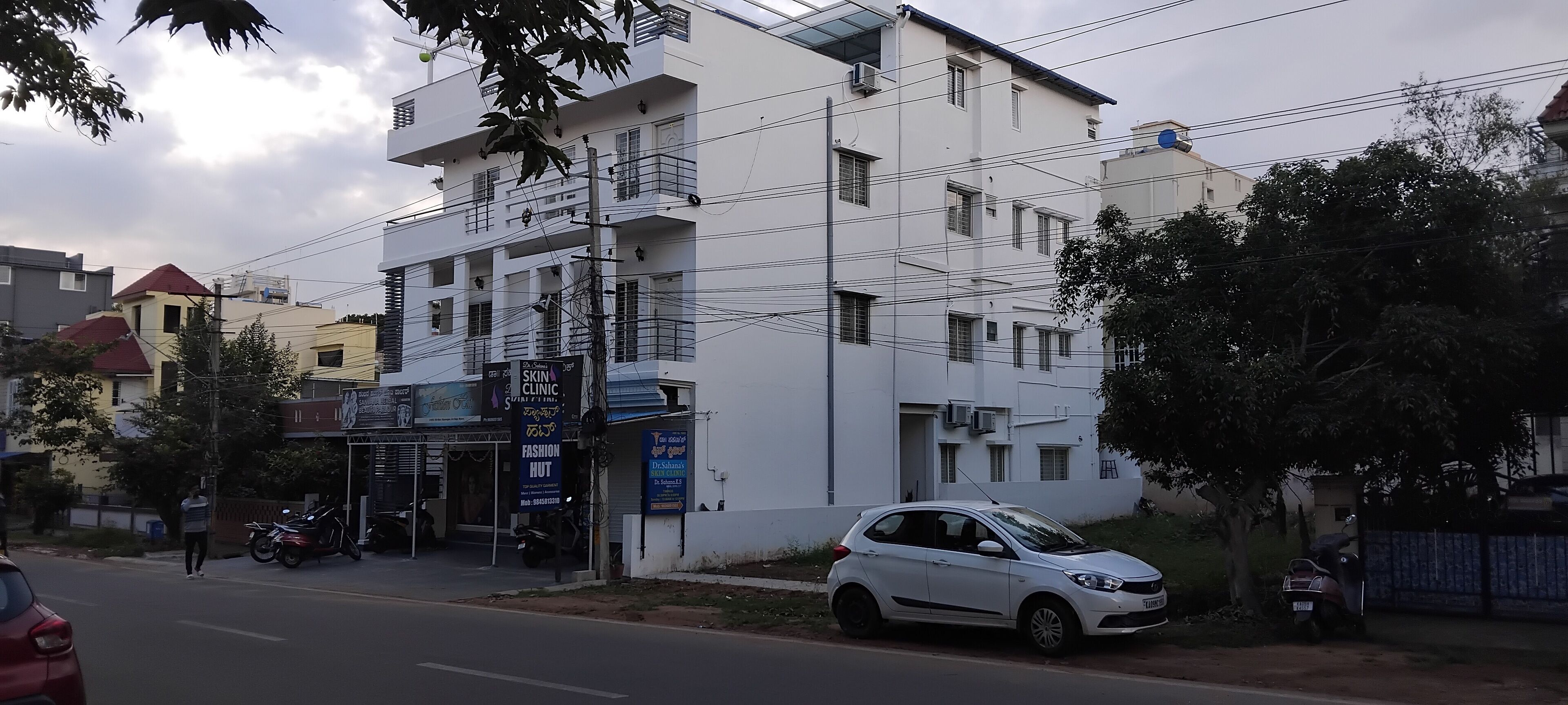 A multi-story building with a ground-floor shop and a white car parked in front.