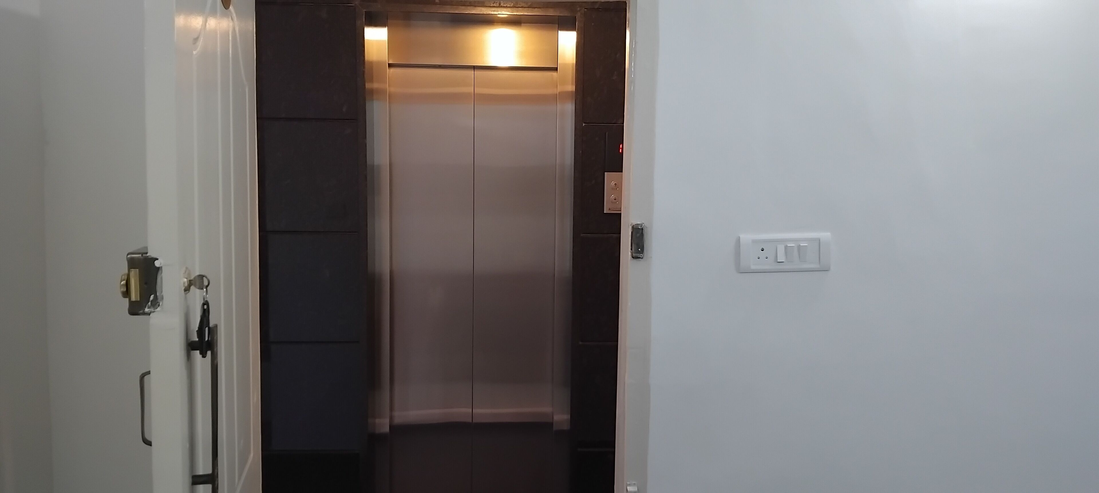 An elevator with a metallic interior and a light fixture at the top.