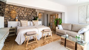 A modern bedroom with a stone accent wall, a large bed, a sofa, and a glass coffee table.