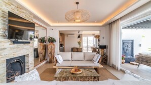 A modern living room with a stone fireplace, a sofa, a coffee table, and a large window.