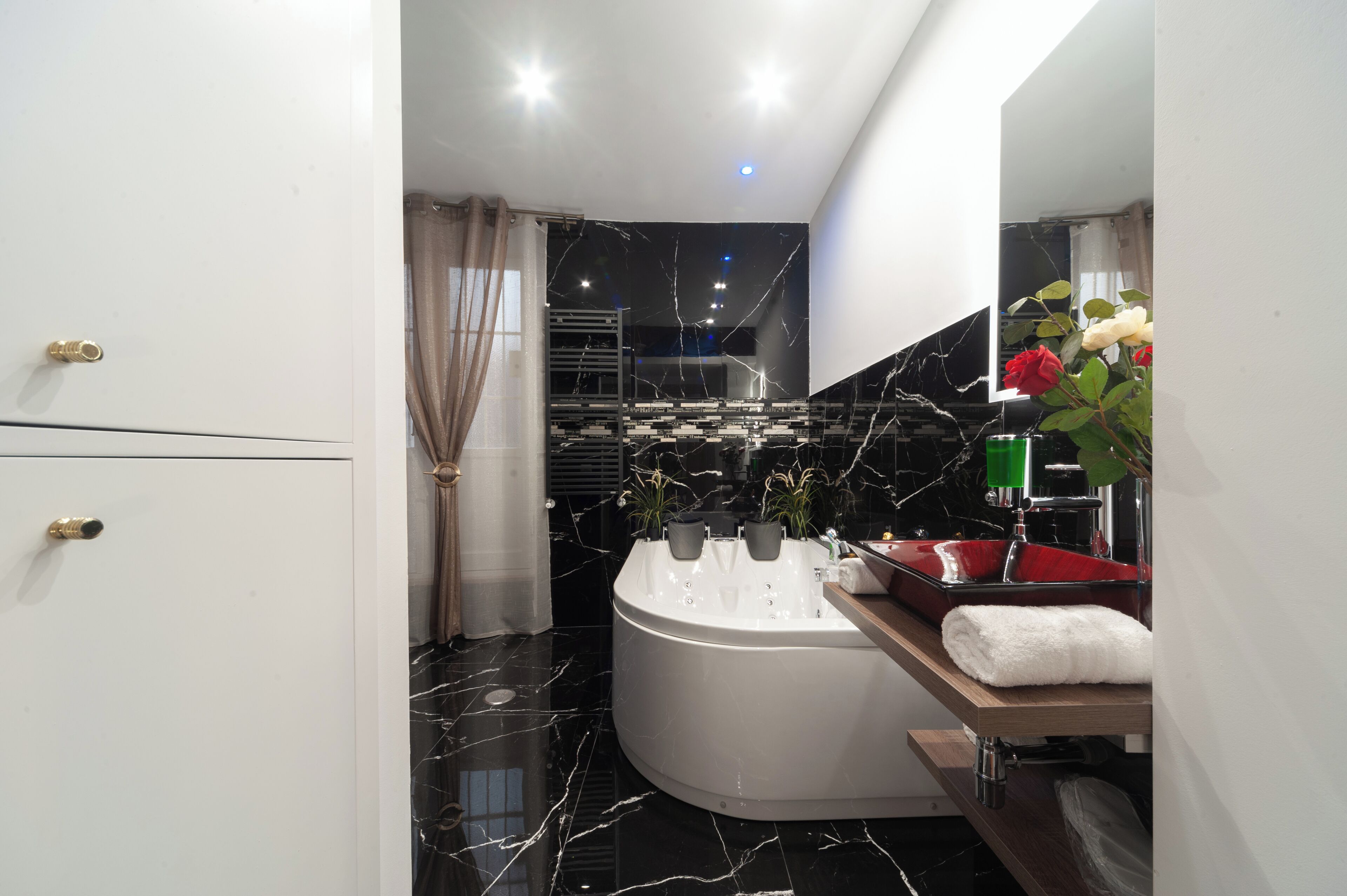A modern bathroom with a large bathtub, a vanity with a mirror, and a shower area.